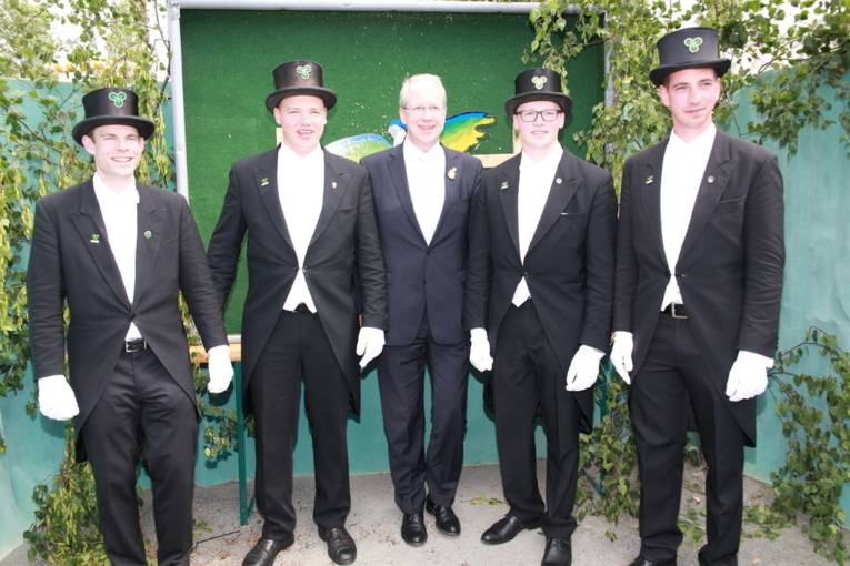 Menschen an einem Schießstand und in einer Festhalle. 