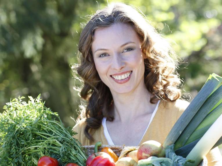 Eine Frau mit einem Korb voller Gemüse.