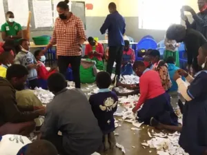 Sch&uuml;ler*innen in einem Klassenraum mit Papierschnipseln auf dem Boden.