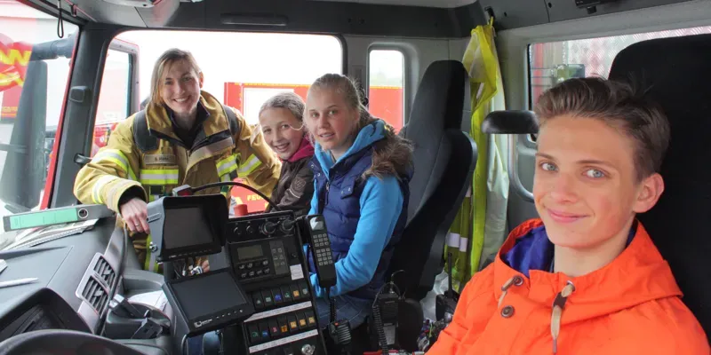 Feuerwehrfrau Stefanie H&ouml;hn erkl&auml;rt den Feuerwehr-Kids die Funktion des Ger&auml;tewagens zur &Ouml;lschadenbek&auml;mpfung.