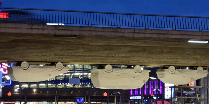 Lebensgroße Pappmachee-Autos hängen unter einer Brücke
