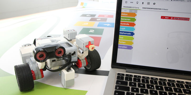 Ein kleiner Roboter neben einem Laptop. Ein kleiner Roboter neben einem Laptop.