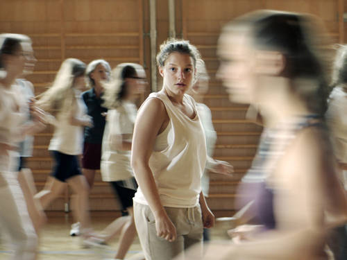 Bild zum Film L'Animale: Mädchen laufen im Sportunterricht. Bis auf das Mädchen im Fokus, was als einzige steht.